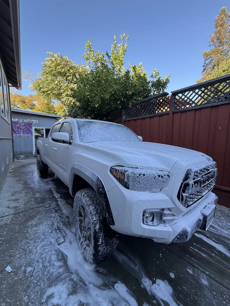 A white Toyota Tacoma covered in foam during a hand wash